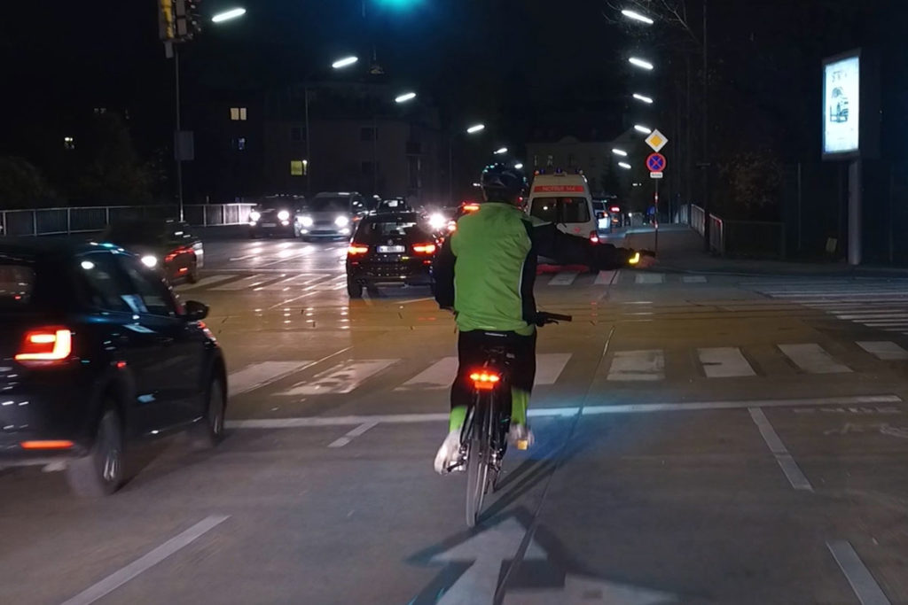 Fahrradfahrer biegt an einer Kreuzung ab und streckt seine rechte Hand mit dem flash2bsafe Handschuh zum blinken aus.